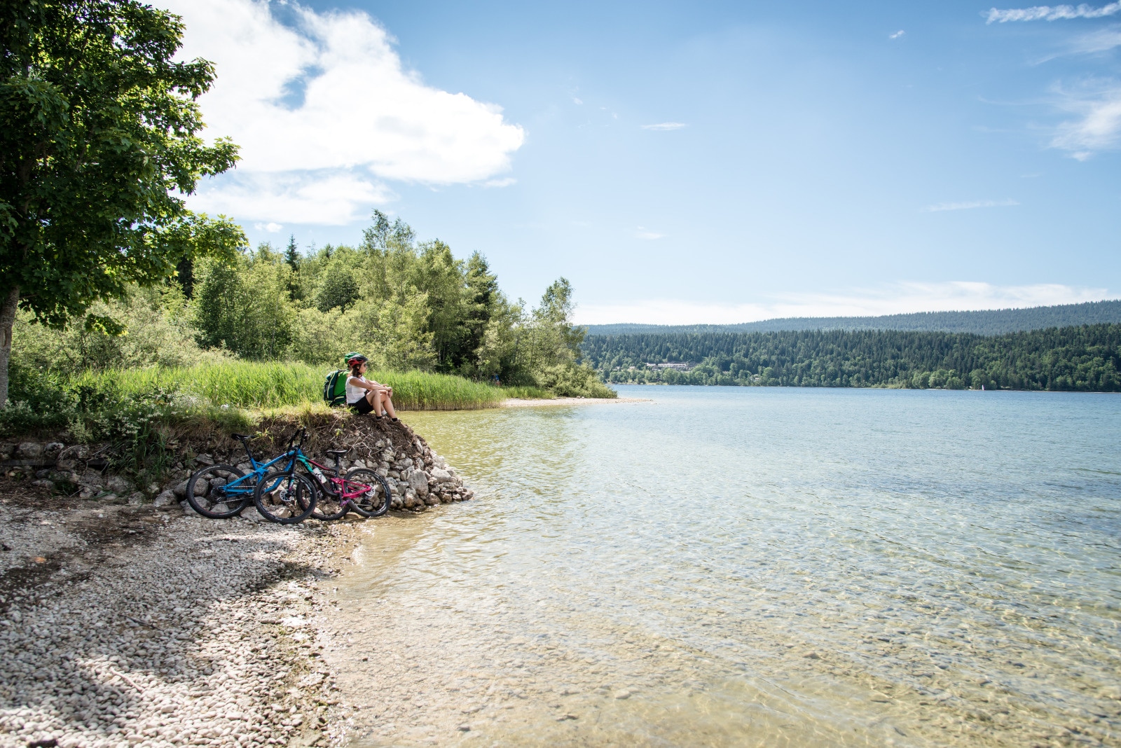 Vallee de Joux Mont Tendre - deux personnes en VTT font une pause au bord du lac à l'eau cristalline